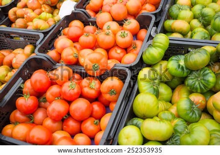 Crates of different types of tomatoes on a street market stall