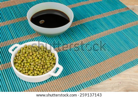 Bowl with soy sauce and soy beans on a bamboo mat