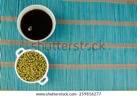 Bowl with soy sauce and soy beans on a bamboo mat