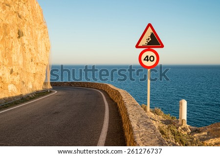 Narrow coastal road winding high up along cliffs