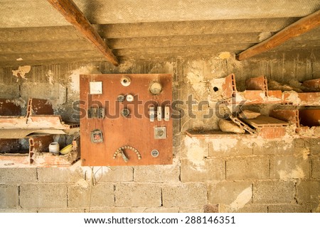 Old switchboard on a wall inside an industrial ruin