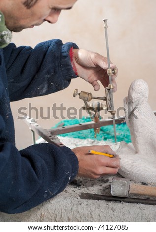 Sculptor working on a marble statue with precision instruments