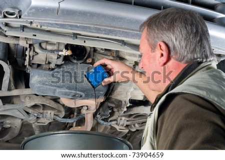 Experienced car mechanic changing oil filter on an engine