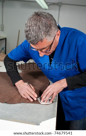 Skilled leather manufacture worker cutting some samples