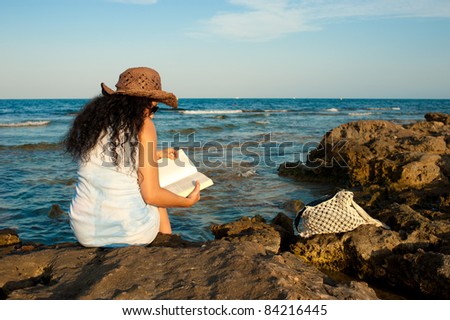 Woman enjoying a book with her feet in the water