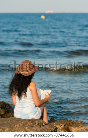 Woman ejoying a book with her feet in the water