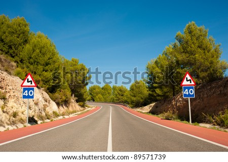 Scenic road with red bicycle lanes running across Mediterranean pine forest