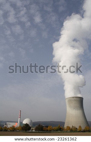 A nuclear power station with a cooling tower in Switzerland - Kernkraftwerk Leibstadt.  Portrait view with very high water vapor plume rising out of the cooling tower against a blue sky.