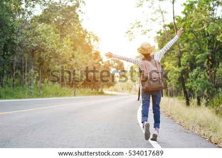 Happy Asian girl backpack  in the road and forest background, Relax time on holiday concept travel ,color of vintage tone and soft focus