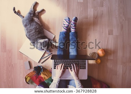Creative workspace: girl working at the computer assisted by her cat.