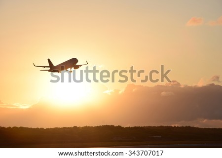 Airplane in the air and sunset in background