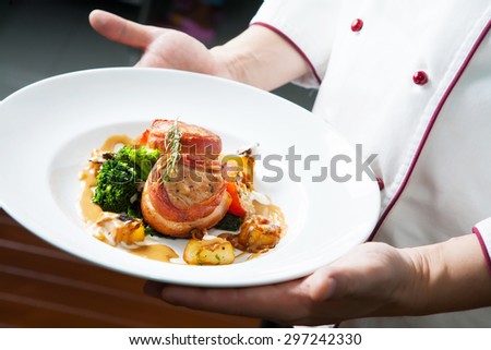 Grilled bbq steak wrapped in prosciutto on chef hand