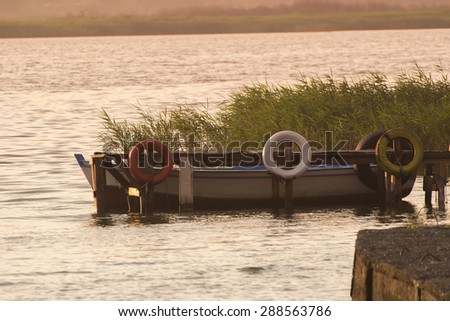 small bridge dock and ship with sunrise over lake