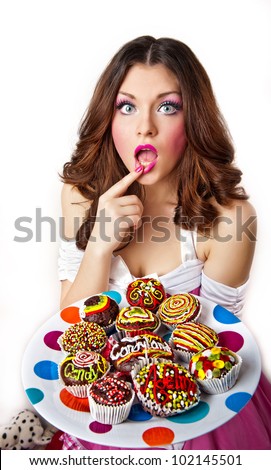 Portrait of young surprised woman eating cakes isolated on white background