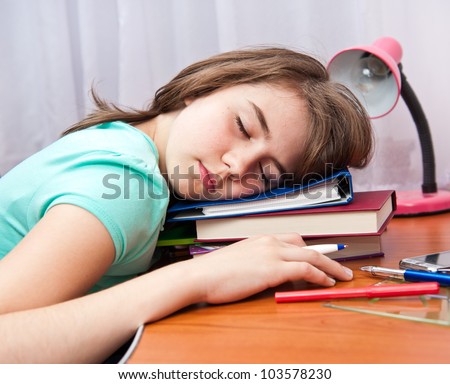 Portrait of a cute teenage girl sleeping on a stack of books at her desk