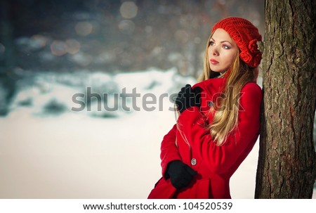 Attractive blonde girl with gloves, red coat and red hat posing winter snow