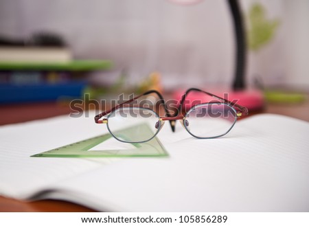 library desk with books, glasses , pen and drawing tools