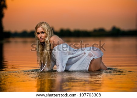 sexy blonde woman in water at sunset .Beautiful swimsuit model in the water