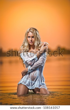 sexy blonde woman in water at sunset .Beautiful swimsuit model