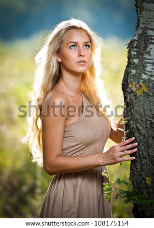 Portrait of a sensual young blonde female on field in sexy short brown dress