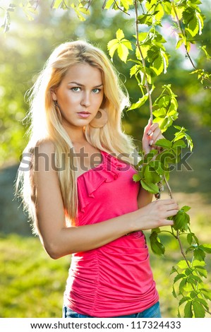 Young attractive sexy  girl with red shirt and blond hair outdoor on the field.Golden lady in autumn day