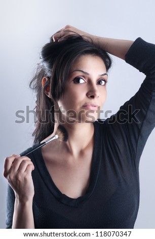 young woman with a makeup brush .makeup  woman smiling closeup. Beautiful young woman applying foundation powder or blush with makeup brush. Isolated on white background.   Caucasian model.