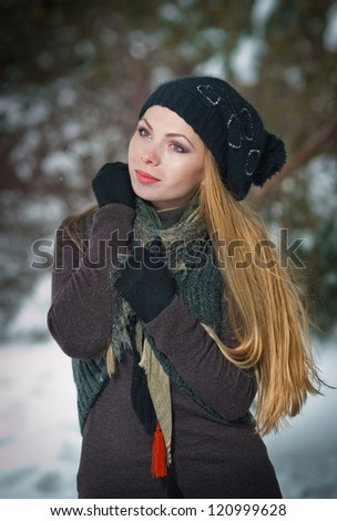 Winter portrait of attractive girl in cap and warm clothes, in park.Beautiful blond hair girl i winter clothes .attractive smiling woman portrait on snow background