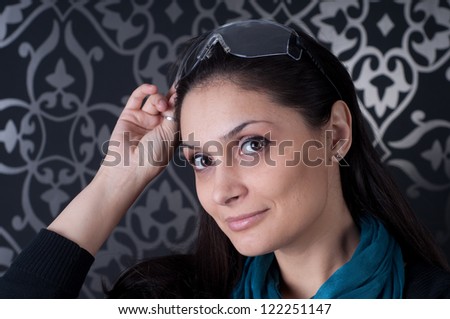 Funky indoor portrait of brunette with blue scarf .Portrait of smiling young woman wearing  glasses.Beautiful woman wearing sunglasses