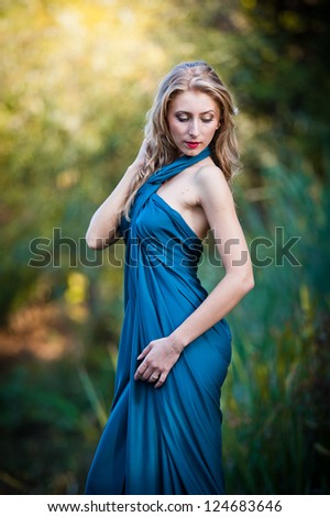 young women in a blue long dress at sunset in a  forest .Beautiful young woman in blue dress in garden on sunset . pretty young blonde in a teal green prom dress  outdoors in a field