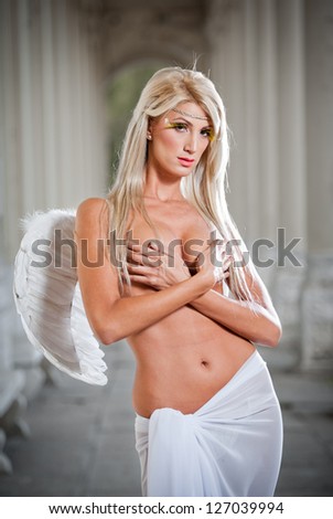 Beautiful blonde angel with white light wings and white veil posing outdoor.Sweet angel . young blond haired woman with white wings like an angel .Beautiful angel woman