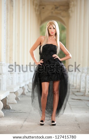 Beautiful woman in black dress posing outdoor.Sexy woman in stylish retro scene.Elegant woman in black dress.Portrait of pretty woman standing in black elegant dress outdoors