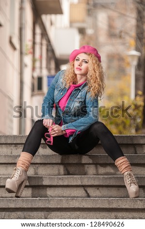 Beautiful fashion woman with pink cap sitting on stair .Young fashionable beautiful girl sitting on stair and looking around