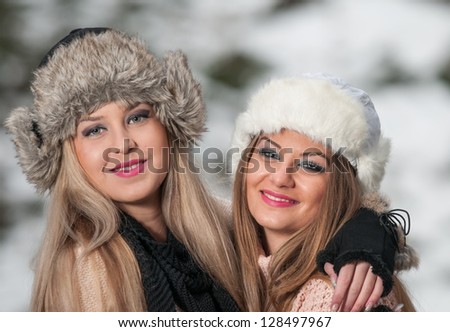 attractive young women in a winter fashion shot.Winter wild girls on snow.Winter Girls with beautiful make up, and snow flake, forest background.Portrait of attractive girls