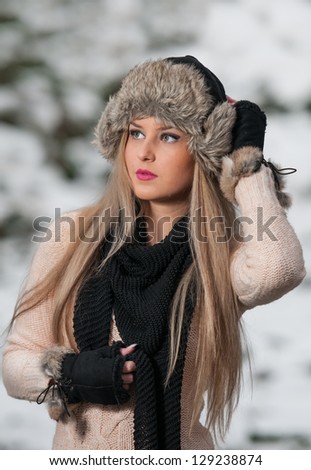 pretty young woman in a winter fashion shoot.Winter wild girl on snow.Winter Girl with beautiful make up, and snow flake, forest background.Portrait of attractive girl
