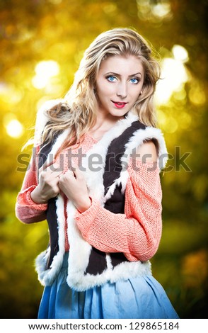 Beautiful elegant woman with long legs in autumn park .Young pretty woman at the autumn park. Beautiful woman spending time in park during autumn season .Young pretty woman at the autumn park