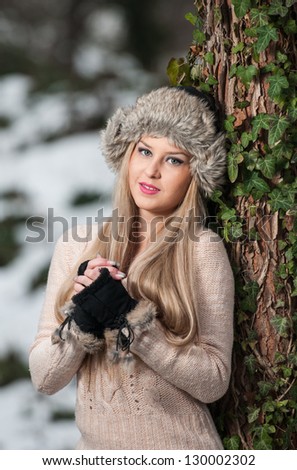 pretty young woman in a winter fashion shot.Winter wild girl on snow.Winter Girl with beautiful make up, and snow flake, forest background.Portrait of attractive girl