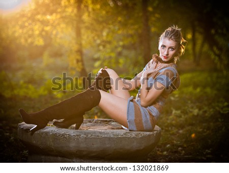 beautiful sexy girl with long leather boots and short dress posing in park in autumn day.Beautiful elegant woman in autumn park .Young pretty woman with long legs in the forest.