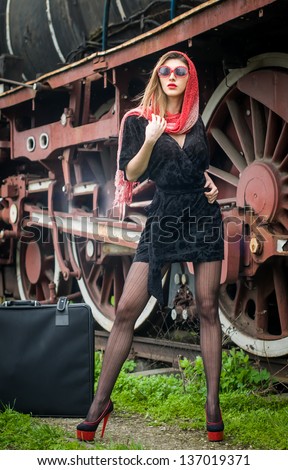sexy attractive girl waiting for landing on the platform in the vintage train.Vintage woman in twenties style waiting for the train.Retro-styled woman with suitcase on the platform waiting for train
