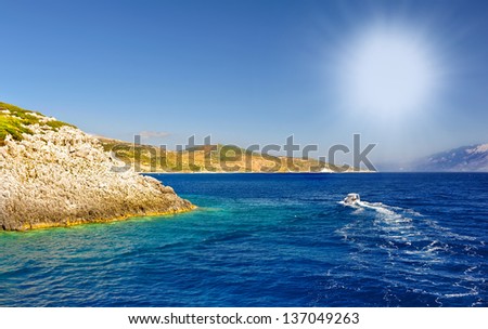 Motor boats with high rock against azure sea and blue sky in Zakynthos.Motor boat missing Zakynthos Island in Greece.Motorized cruiser boat in the blue sea of  island in Greece.
