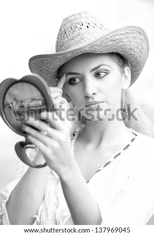 beautiful woman with straw hat and mirror .Young woman looking in cosmetic mirror .Good looking beautyfull  woman doing make-up in front of mirror.