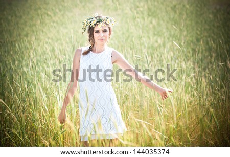 Young girl with wreath on golden wheat field.Portrait of beautiful blonde girl with wreath of wild flowers.Beautiful woman enjoying daisy field, pretty girl relaxing outdoor, harmony concept