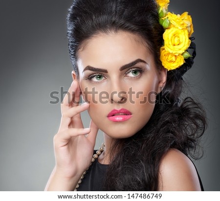 Hairstyle and Make up - beautiful female art portrait with yellow roses.Elegance. Genuine Natural brunette with Flowers. Portrait of a attractive woman with beautiful eyes and flowers in her hair.