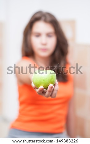 teen Girl holding a beautiful, fresh green apple indoor, selective focus on apple.Pretty teen girl concentrated  hold green fresh apple in hand.. girl holding an green apple, healthy eating