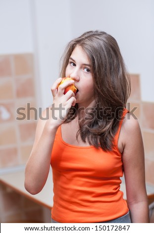 Pretty teen girl eating peach, indoor.Beautiful teenage girl biting an peach .Picture of beautiful teenage biting a peach