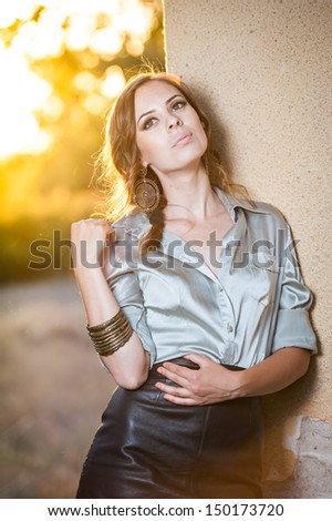 Elegant glamour woman wearing  brown skirt and blouse outdoor in the park at sunset. Beautiful woman in skirt and blouse.Slim girl in white blouse relaxing