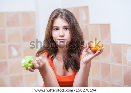 Pretty teen girl eating fruits, indoor. Beautiful teenage girl holding a green apple and a peach in her hands. Picture of beautiful teenage eating a green apple and holding a peach