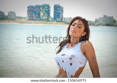 portrait of young sexy brunette girl in white bikini and wet t-shirt at the beach.Sensual attractive woman in water wearing bikini and long legs . Woman with perfect body relaxing on the beach.
