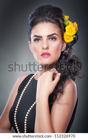 Hairstyle and Make up - beautiful female art portrait with yellow roses and beads.Elegance. Natural brunette with flowers. Portrait of a attractive woman with beautiful eyes and flowers in her hair.