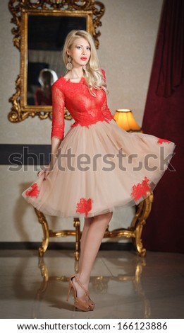 Young beautiful luxurious woman in elegant dress. Beautiful young blonde woman with a mirror in background. Seductive blonde woman in luxury manor, vintage style