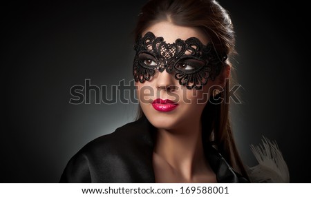 Portrait of attractive sensual young woman with mask. Young attractive brunette lady posing on dark background in studio. Portrait of the beautiful fashion sexy woman with red lips and mask indoor